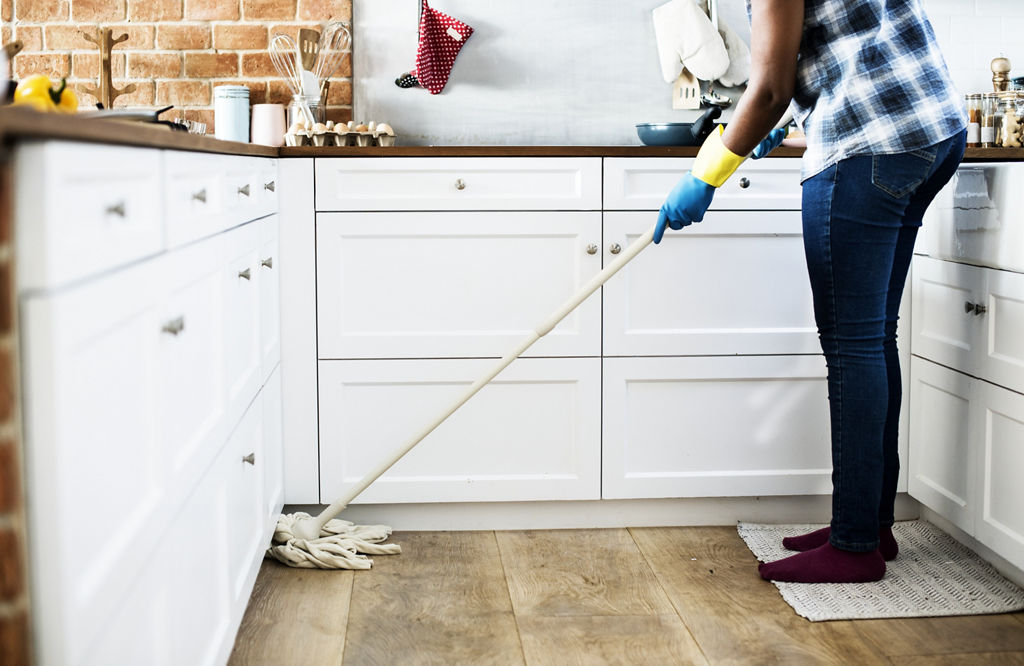 Man mopping apartment kitchen floor